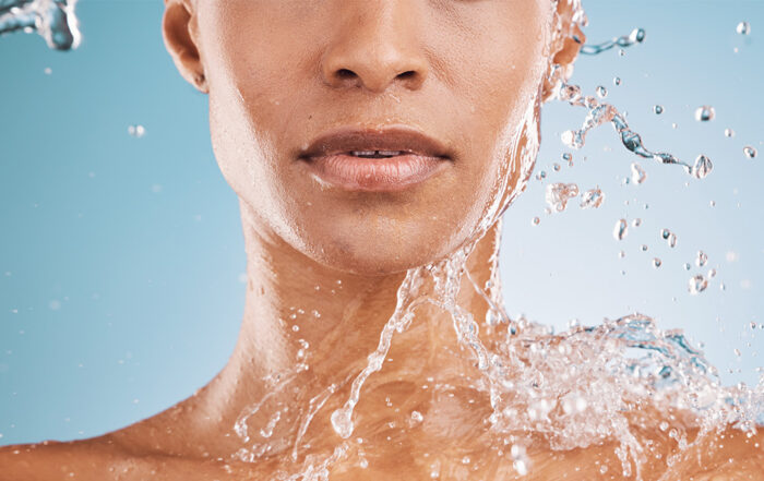 a woman on a blue background with a water splash emphasising skin hydration
